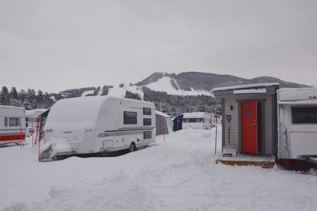 Asuntovaunuja, joihin on liitetty etuteltta tai -mökki lumisella talvileirintäalueella.