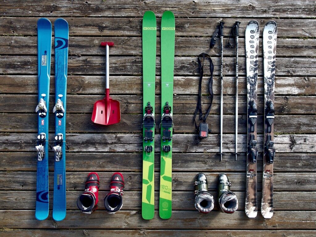 Three pairs of slalom skis and boots on a wooden floor