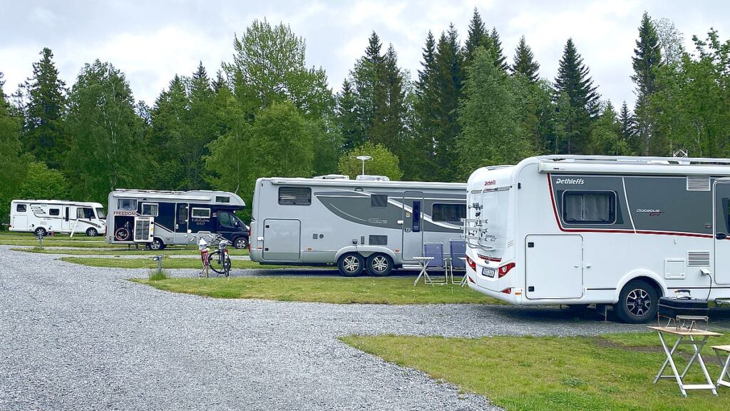 Fyra stora eller medelstora husbilar på en campingplats
