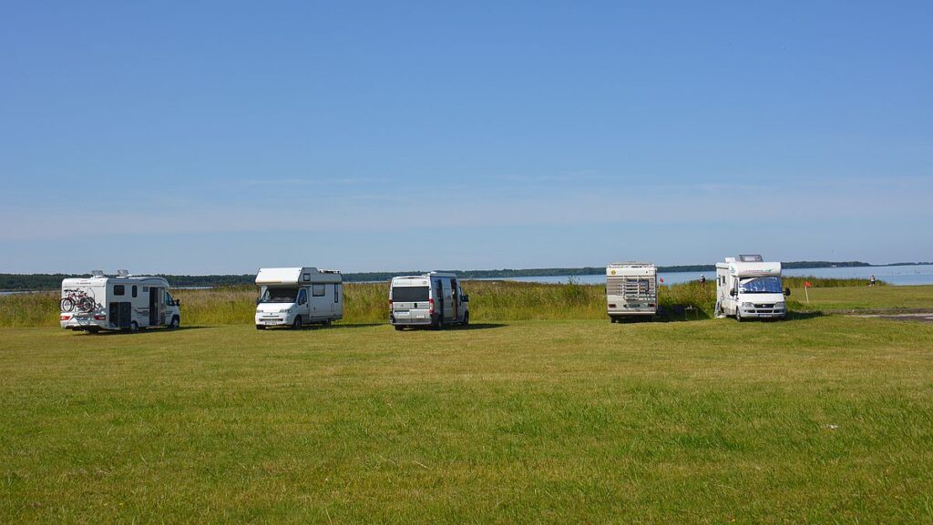 Fem husbilar parkerade på gräs, med hav i bakgrunden