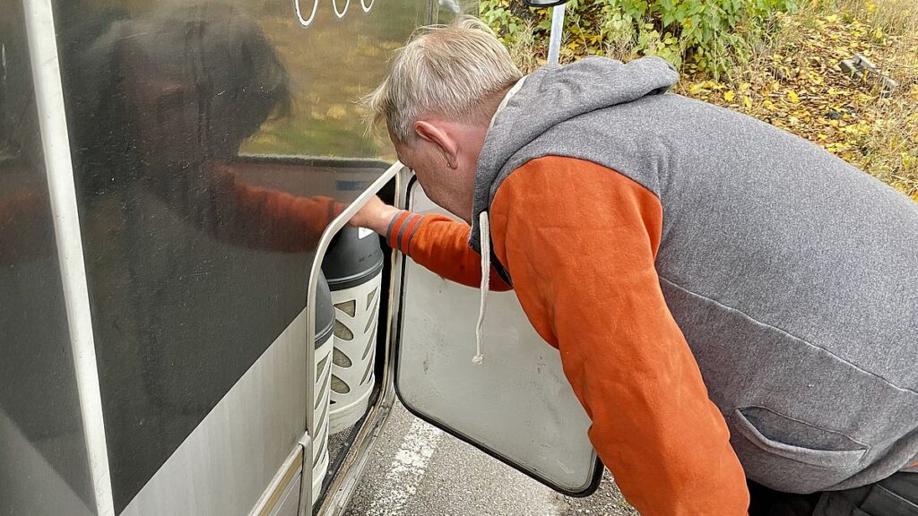 Mies tarkistaa kaasupulloja matkailuautossa