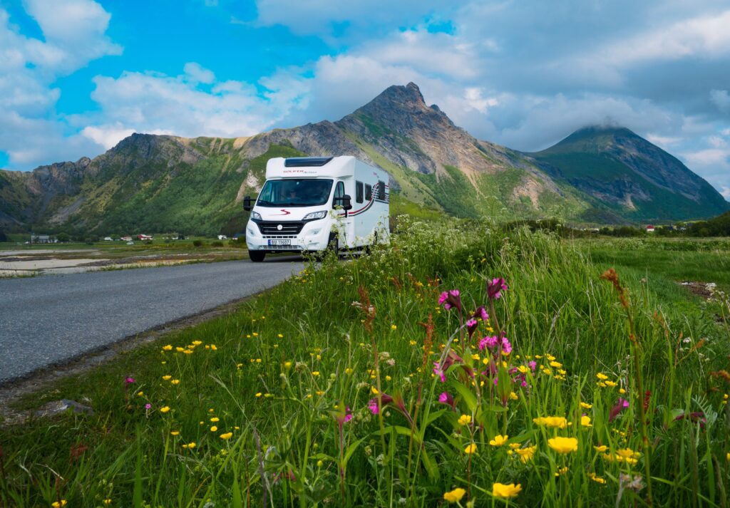 Motorhome in green landscape, mountains in the background.