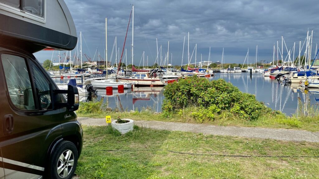 Bobil parkert på en rasteplass, med utsikt over en båthavn