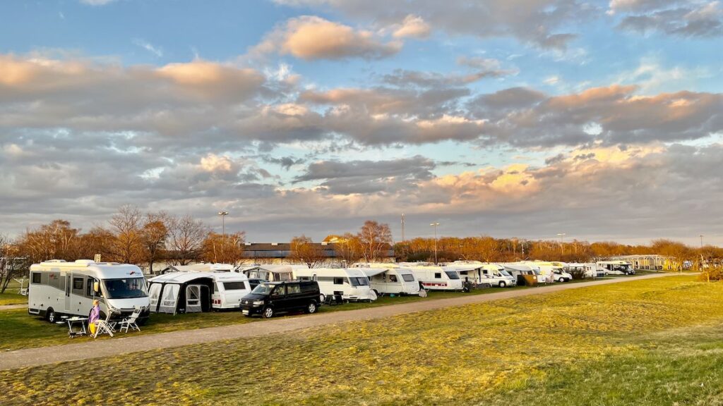 Bobiler og campingvogner på rekke og rad på en campingplass i Skåne, ved solnedgang