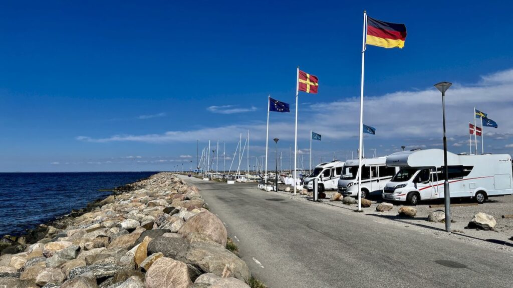 Matkailuautoja rivissä matkaparkissa Skånessa, veden äärellä