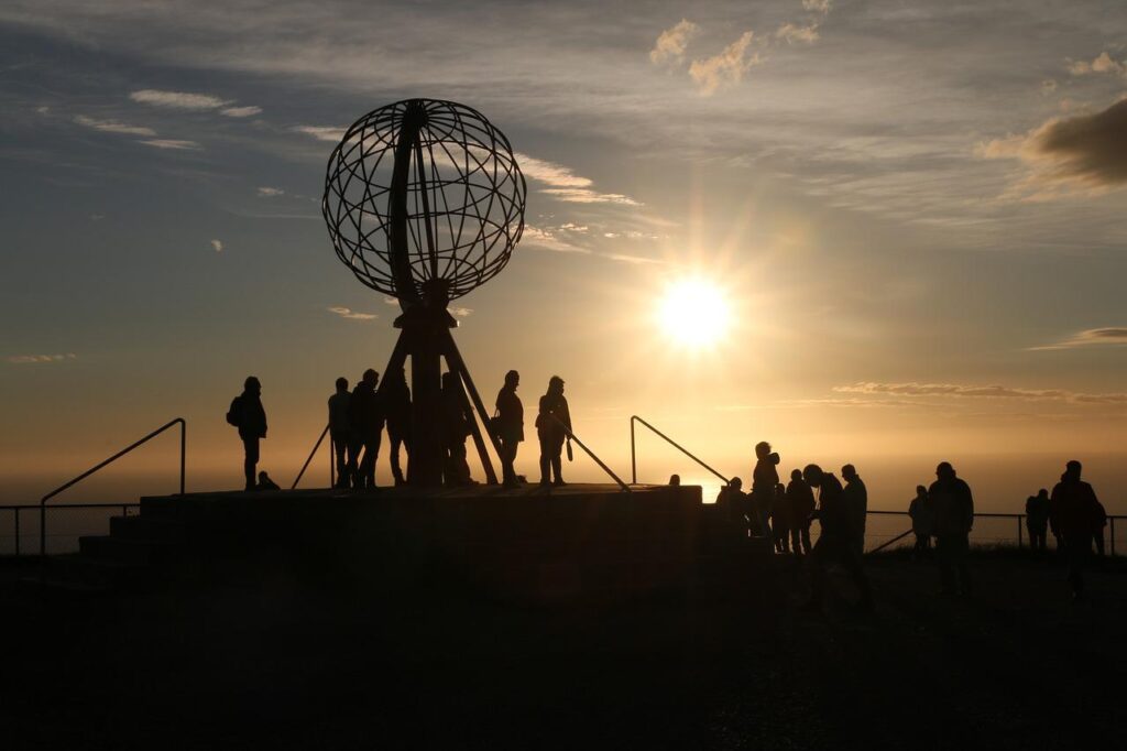 En grupp människor står vid Nordkapsklippan i Nordnorge